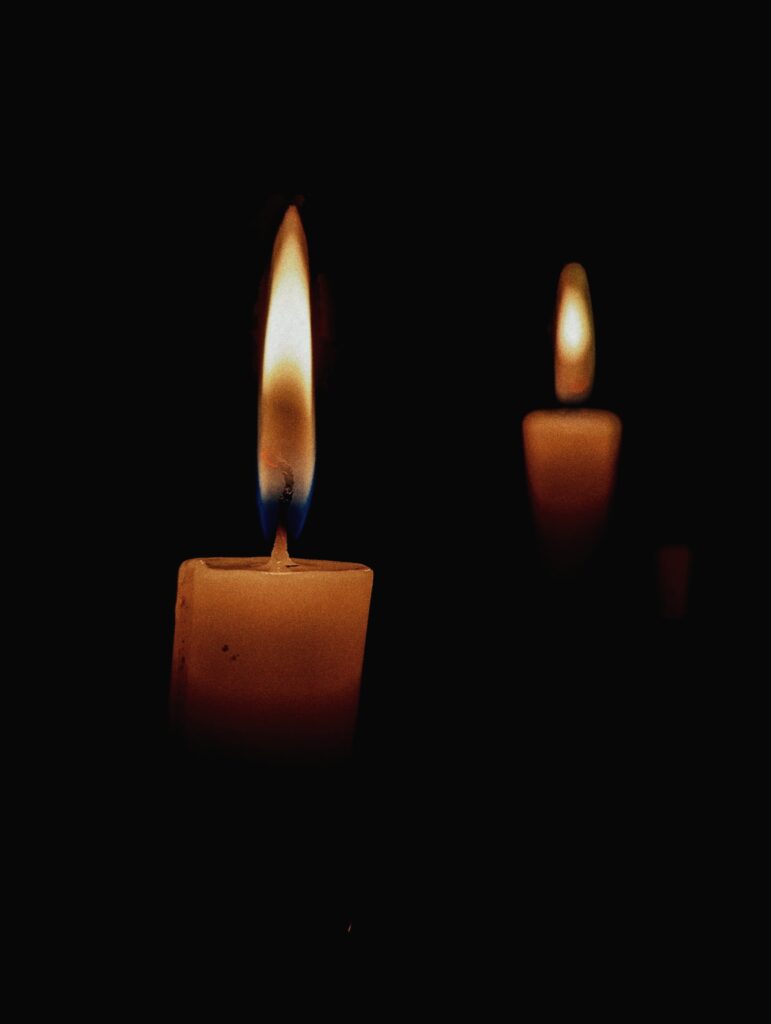 photo of two candles and their flames in the dark.